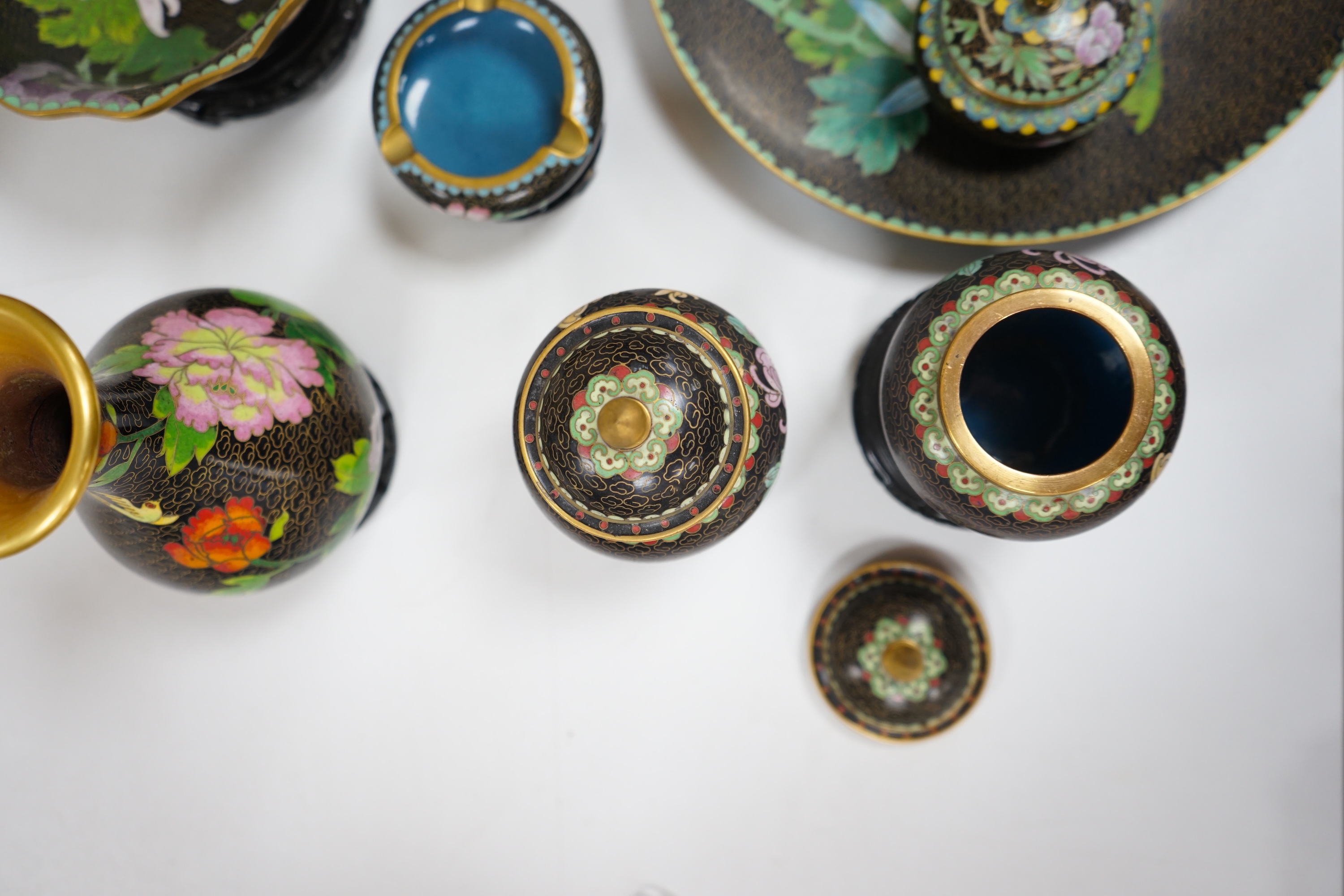 A collection of Chinese cloisonné enamel vessels, some with stands, all worked on a black background in floral designs, plate 26cm diameter. Condition - good